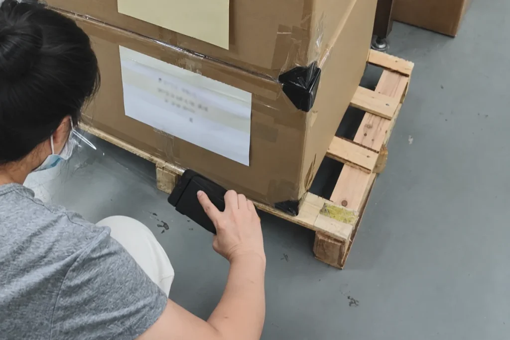 Checking a shipping carton on a wooden pallet before dispatch.