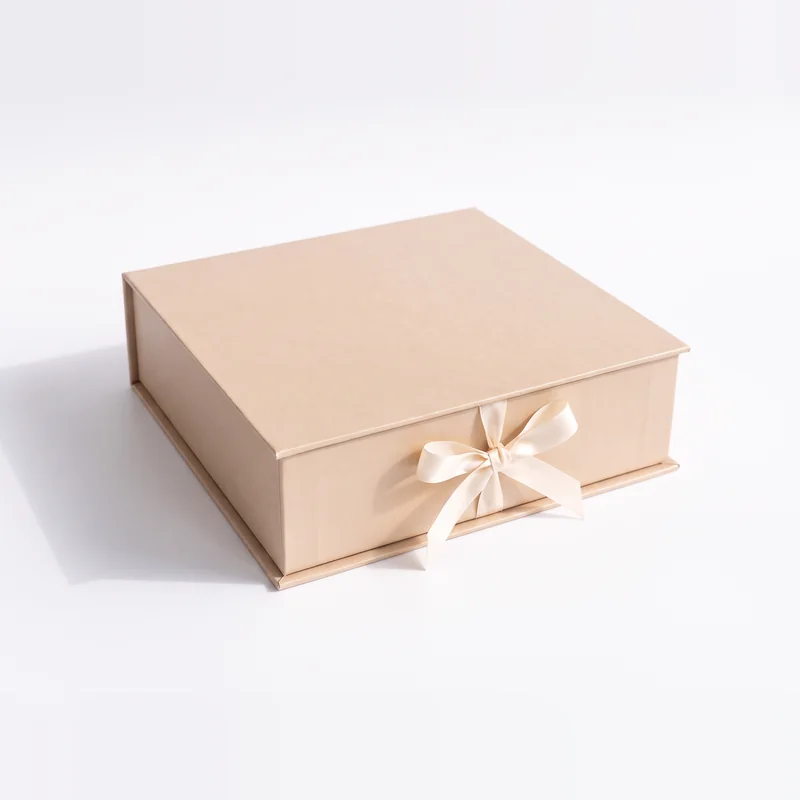 Closed champagne gift box tied with an ivory satin ribbon bow
