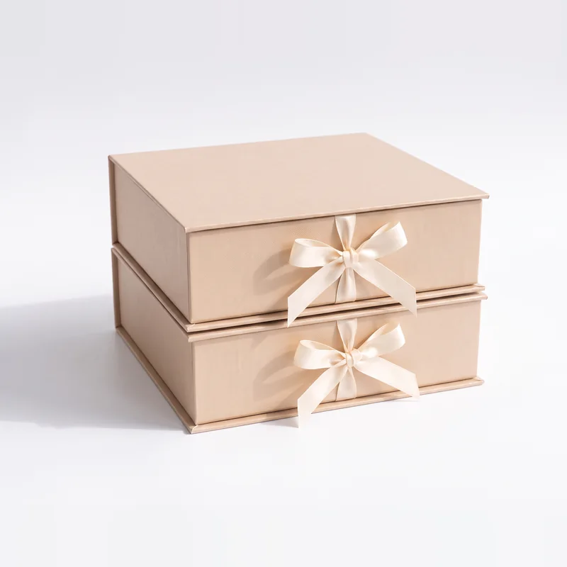 Two champagne gift boxes stacked with ribbon bows