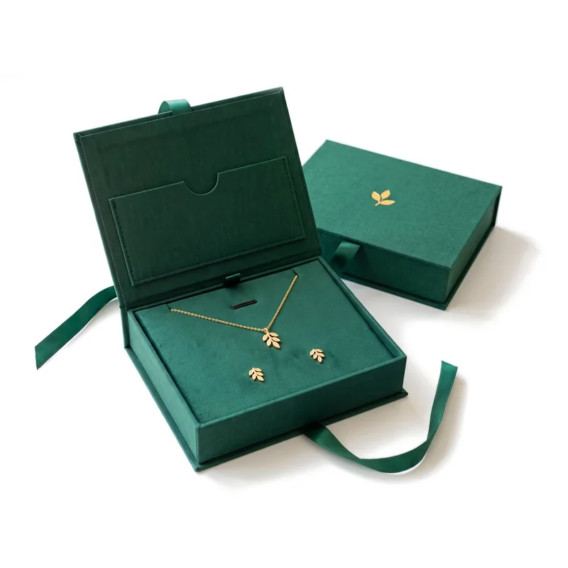 Emerald jewelry gift box open with a gold leaf necklace and earrings