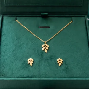 Close-up of a gold leaf necklace and earrings on an emerald velvet pad