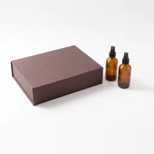 Closed espresso brown box with two amber spray bottles beside it
