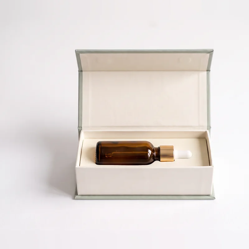 Dropper bottle lying in the white EVA insert of an ivory gift box